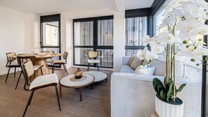 Una sala moderna con comedor, ventanas amplias y una orquídea en maceta.
