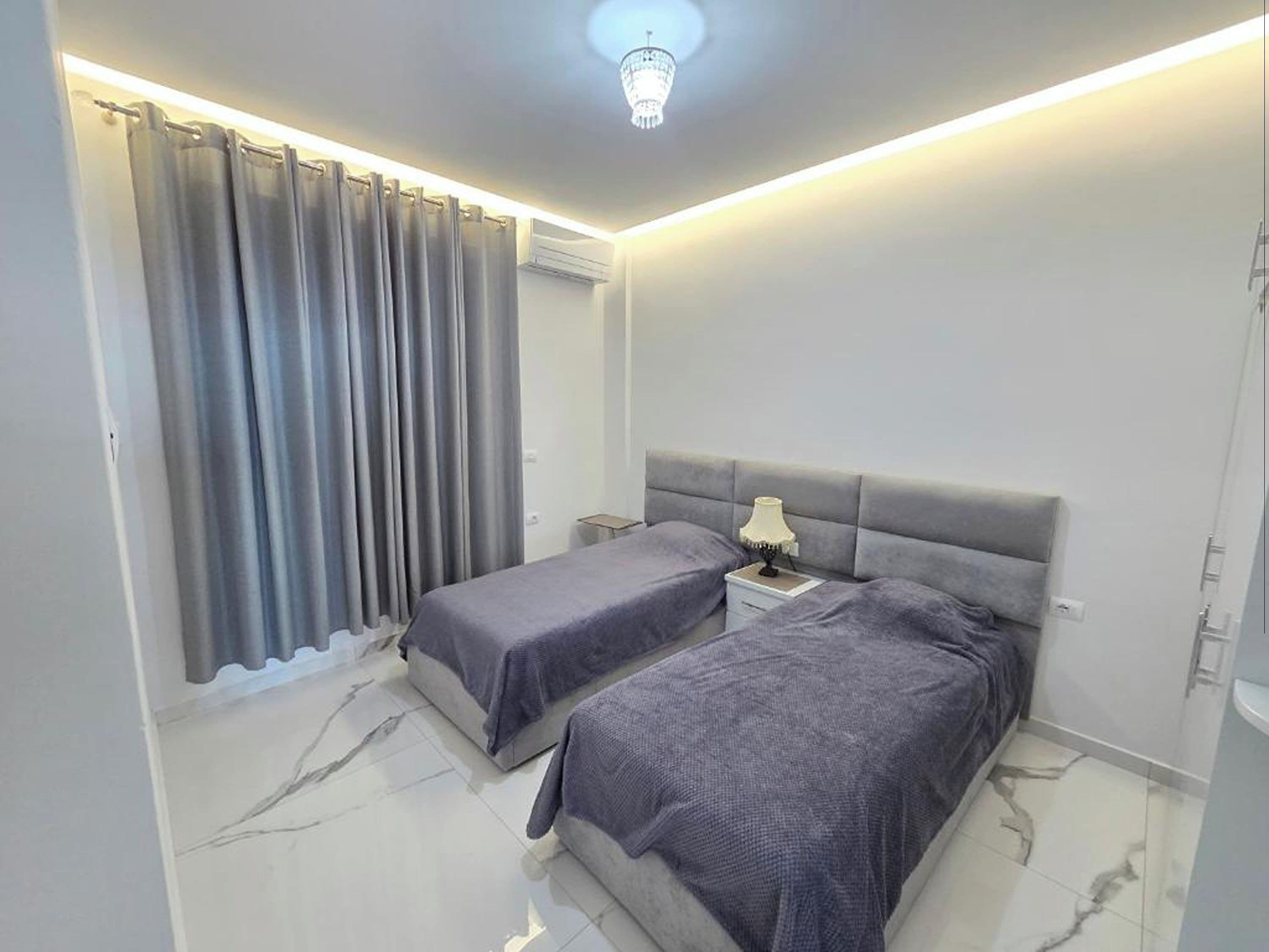 Un dormitorio con dos camas, una mesita de noche, una lámpara y una luz en el techo.
