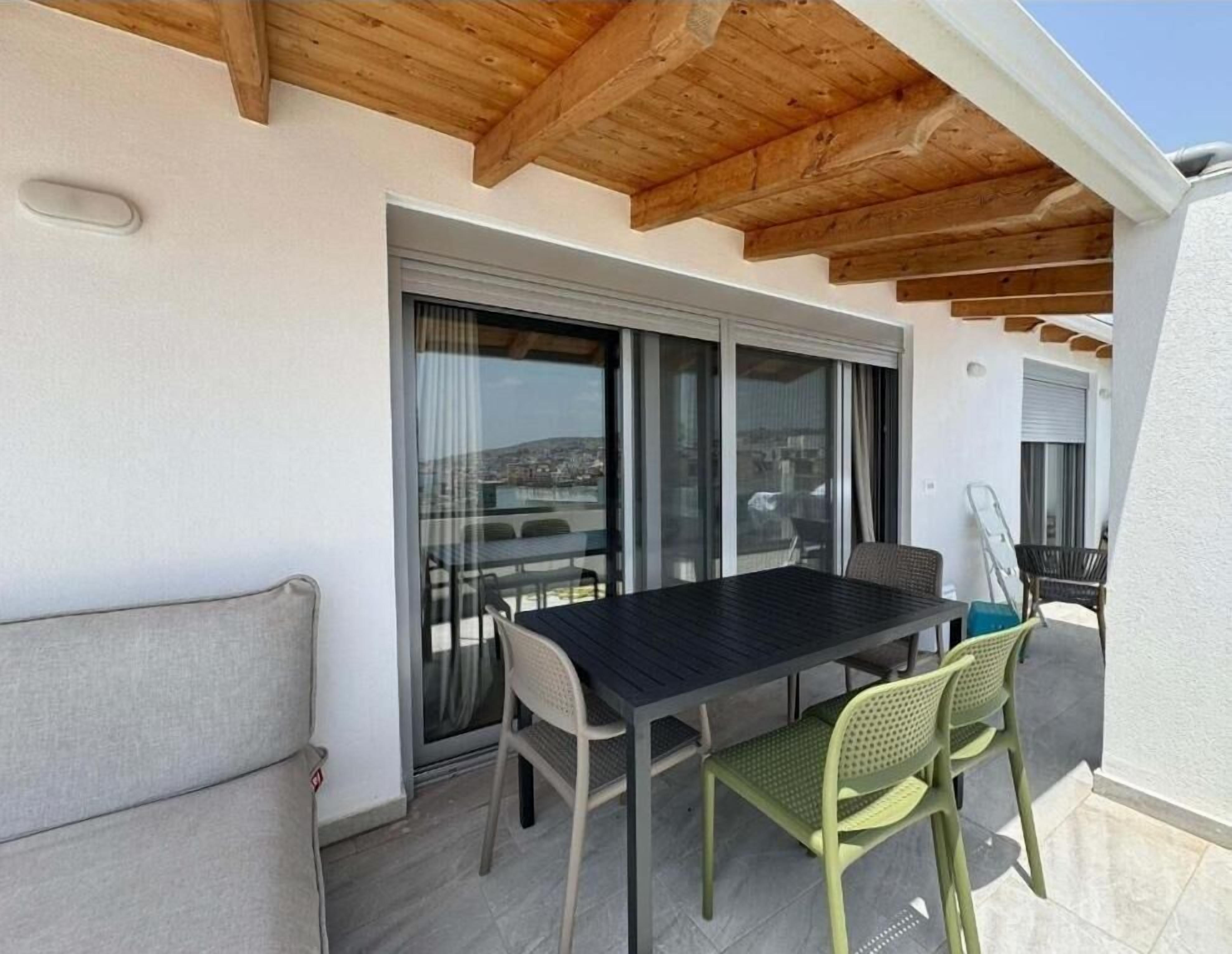 A patio with a table and chairs, a sliding glass door, and a view of the city.