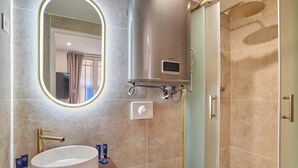 Een badkamer met een rond wastafel, een spiegel, een toilet en een douche.