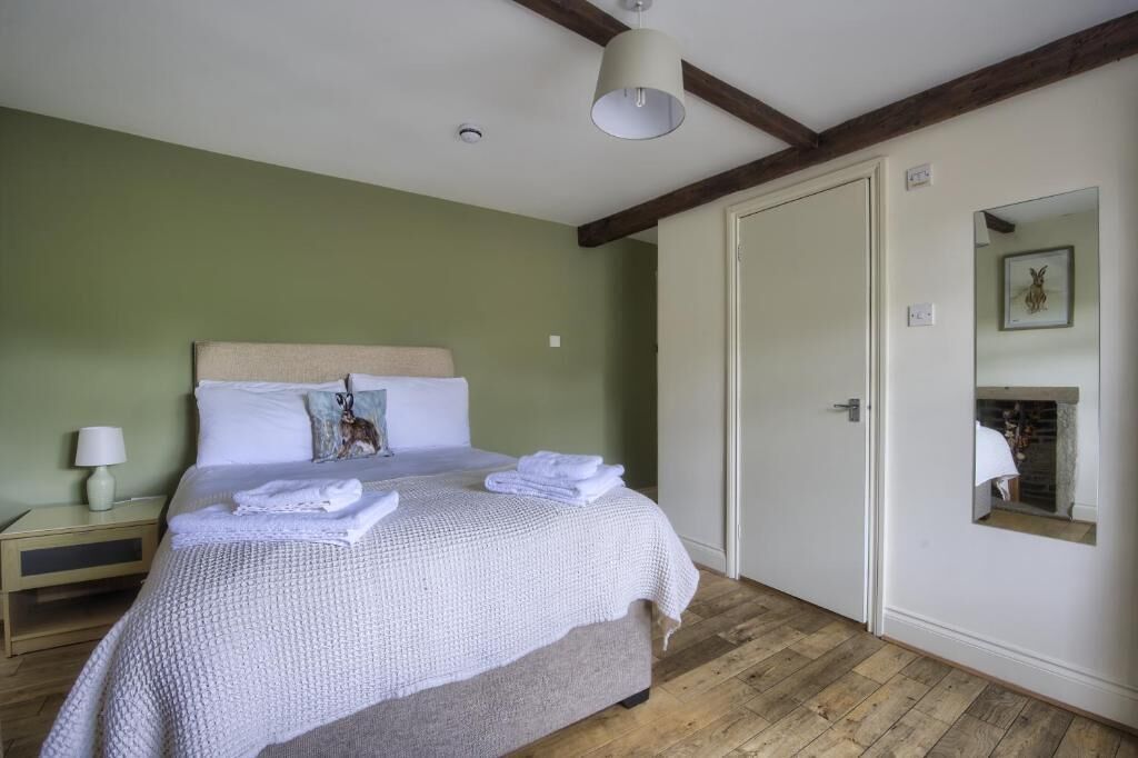 A bedroom with a bed, a nightstand, a mirror, and a door.