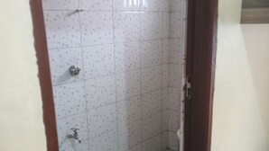 Een kleine badkamer met tegels, voorzien van een douche, toilet en wastafel.