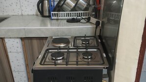 Een keuken met een gasfornuis, een afdruiprek en een waterkoker.