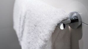 Una toalla blanca colgada en un perchero de cromo en un baño.