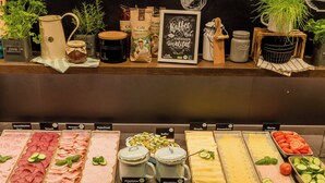 Un bufé con diversas opciones de comida, incluyendo carnes, quesos y verduras.