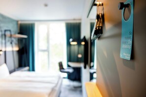 A hotel room with a bed, a desk, and a wall-mounted sign. - Motel One Koblenz (Koblenz)