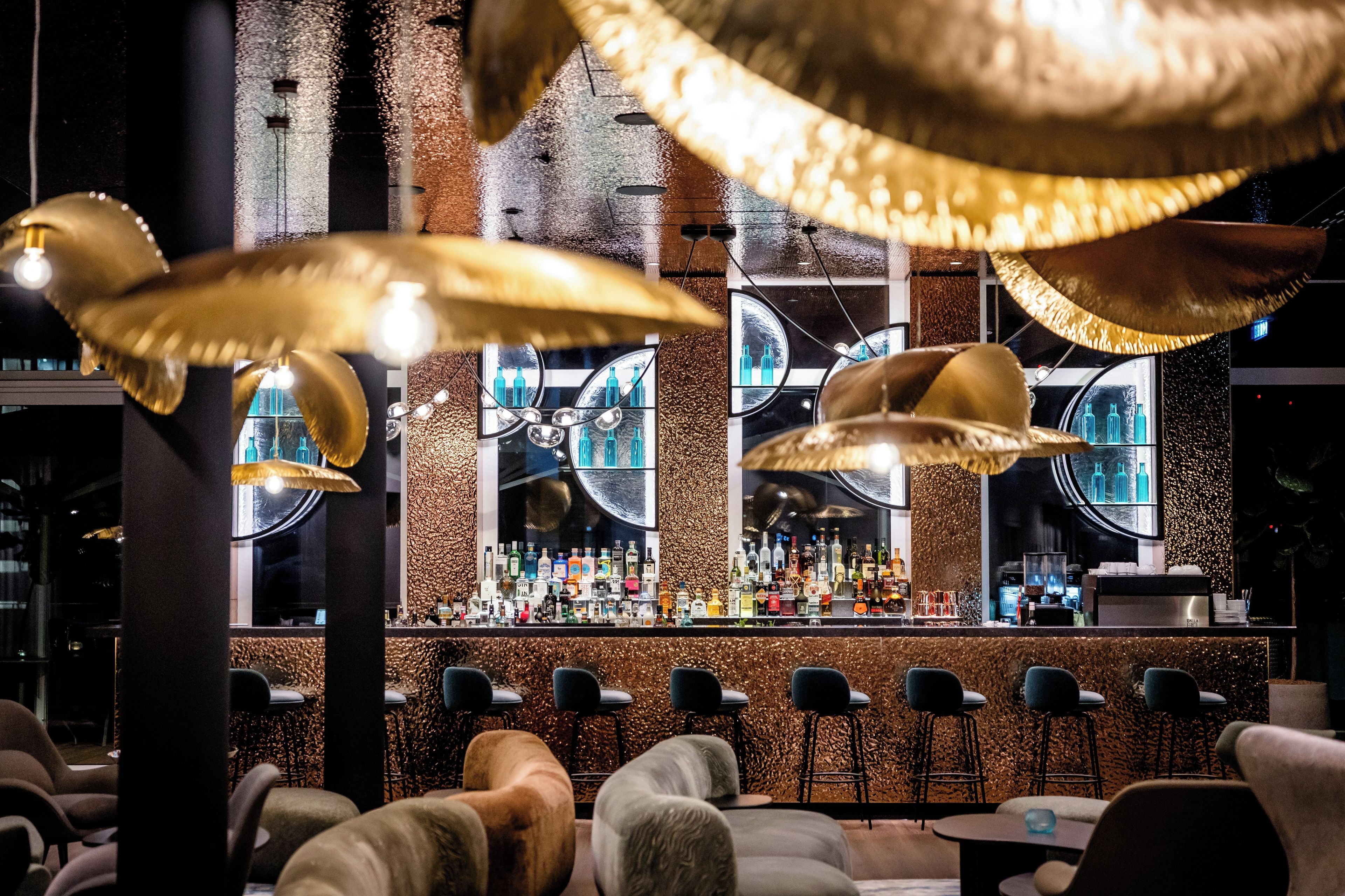 A bar area with multiple seating options and a variety of bottles on display.