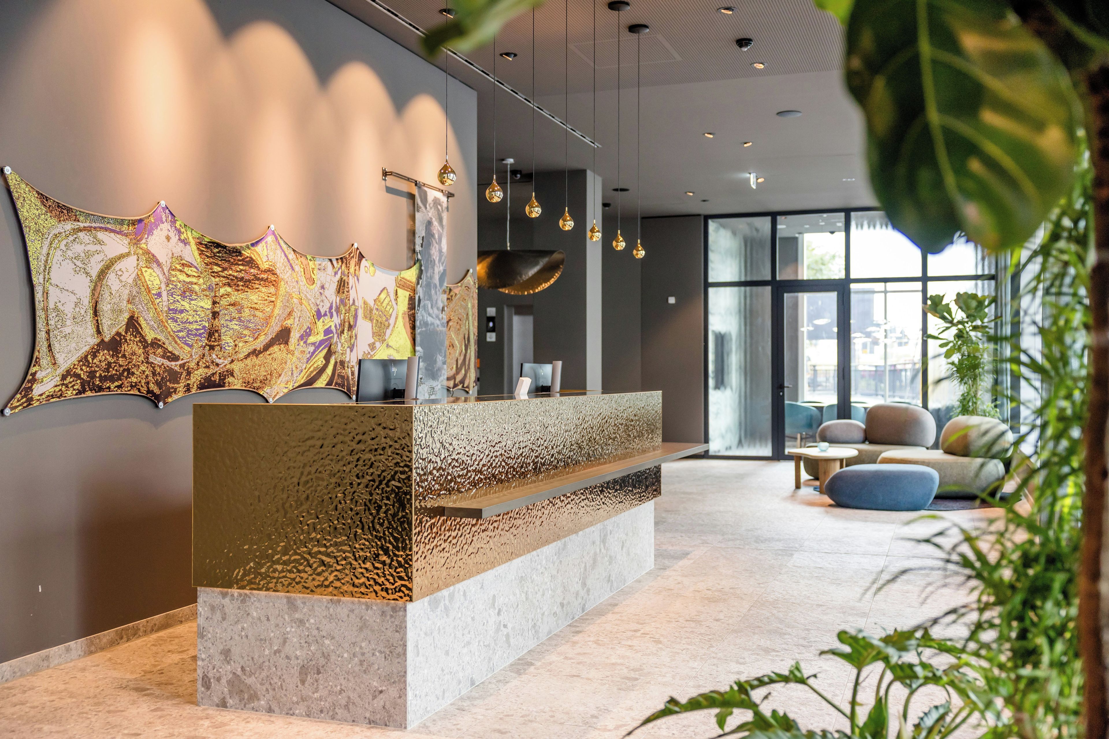 Un área de recepción de diseño moderno, con un mostrador texturizado, una gran obra de arte abstracta en la pared y una zona de estar con vistas amplias a través de grandes ventanales.