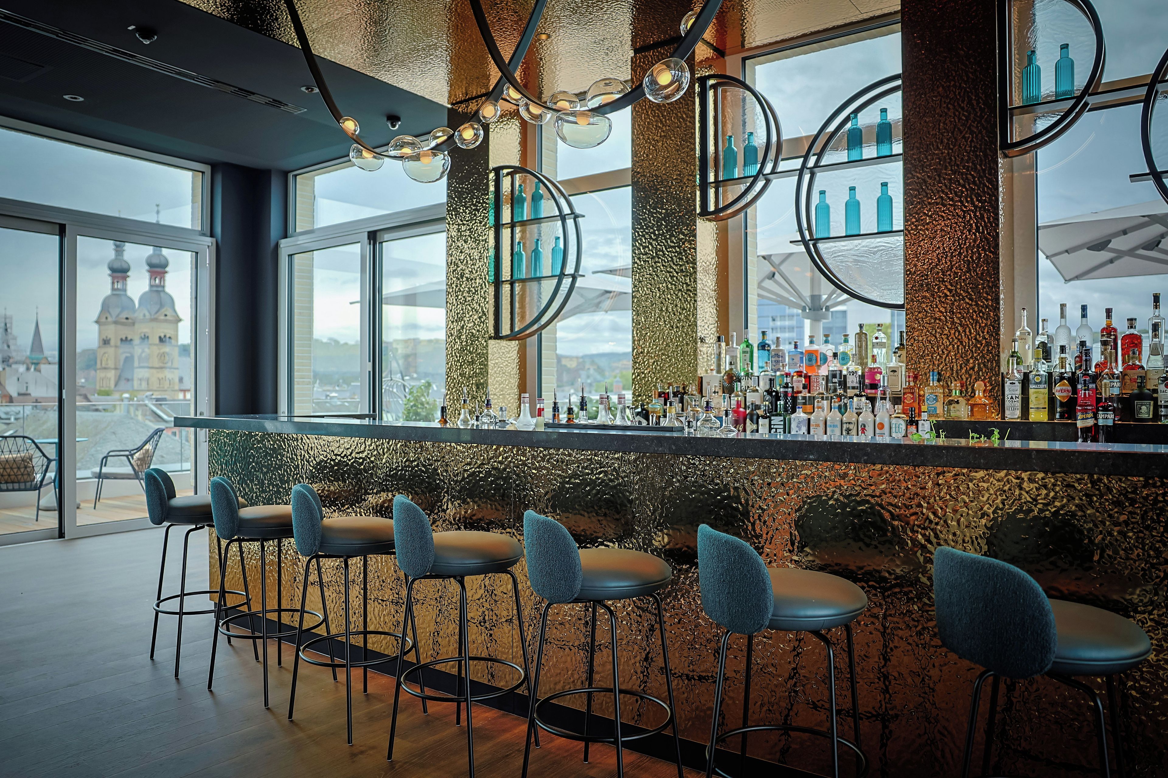 A bar area with multiple stools and a variety of bottles.