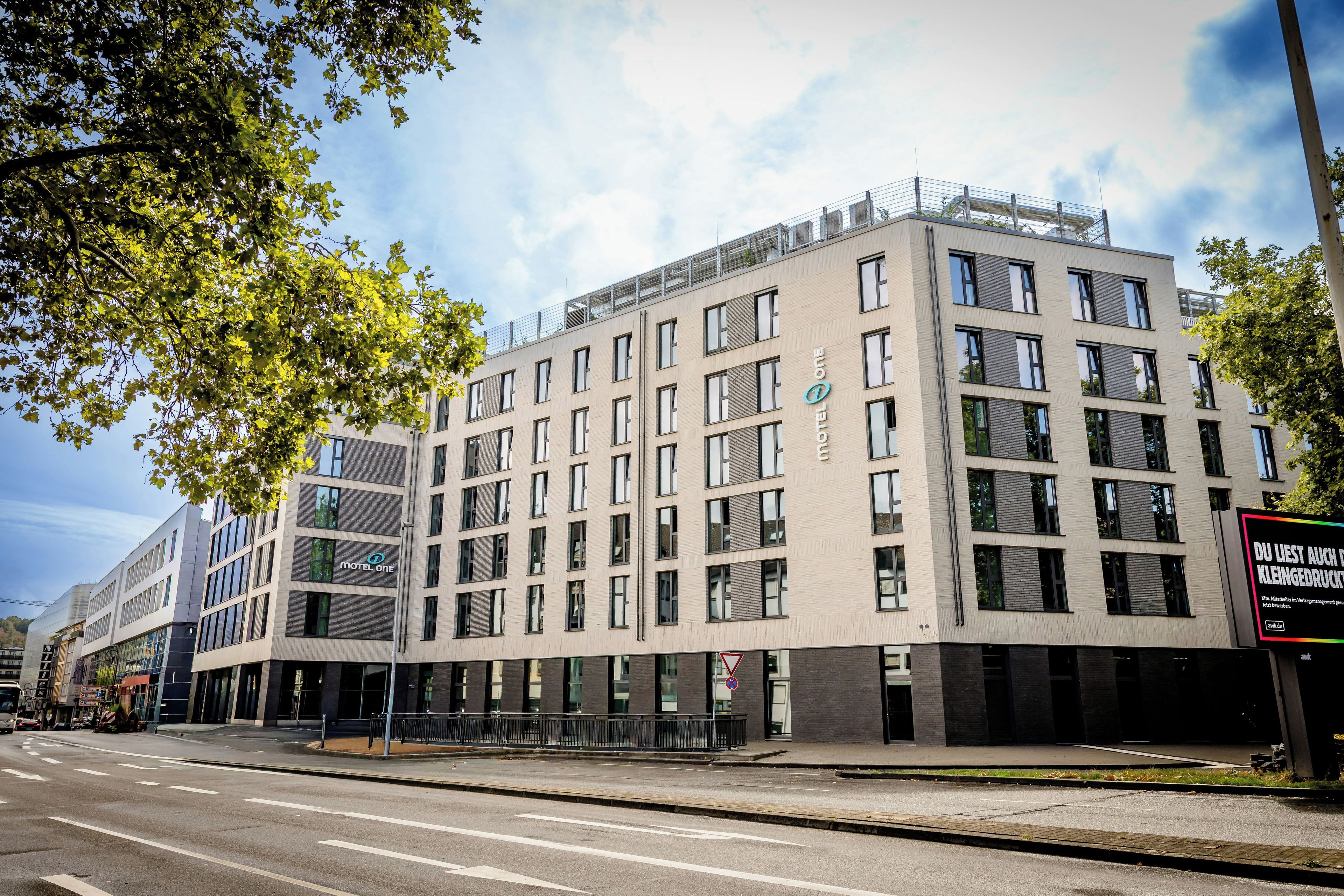Een modern hotelgebouw met meerdere verdiepingen, grote ramen en een opvallend 'Motel One' bord.