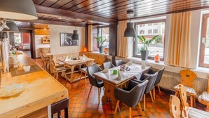 A restaurant with wooden tables and chairs, a bar area, and large windows with curtains. - Hotel Pension Löwen nahe Feldkirch - günstige Zimmer für Urlauber, Firmen und Monteure (Sulz)