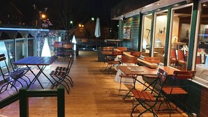An outdoor patio with wooden tables and chairs, a glass railing, and a view of the street. - Hotel Pension Löwen nahe Feldkirch - günstige Zimmer für Urlauber, Firmen und Monteure (Sulz)