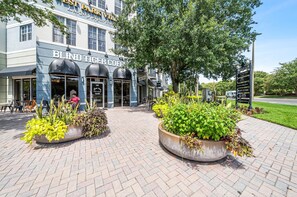 L’entrée d’un hôtel, avec une enseigne indiquant « BLIND TIGER COFFEE », et un trottoir dallé agrémenté de jardinières.
