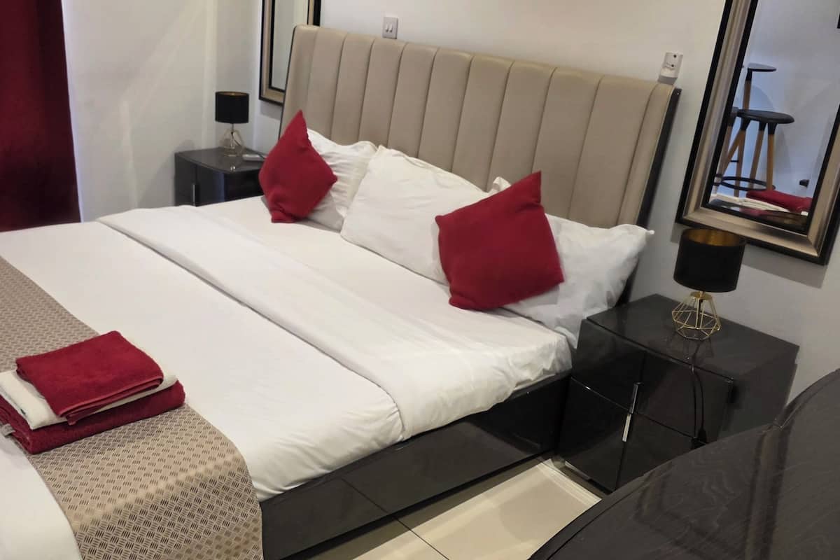 A hotel room with a bed, a nightstand, a lamp, and a mirror.