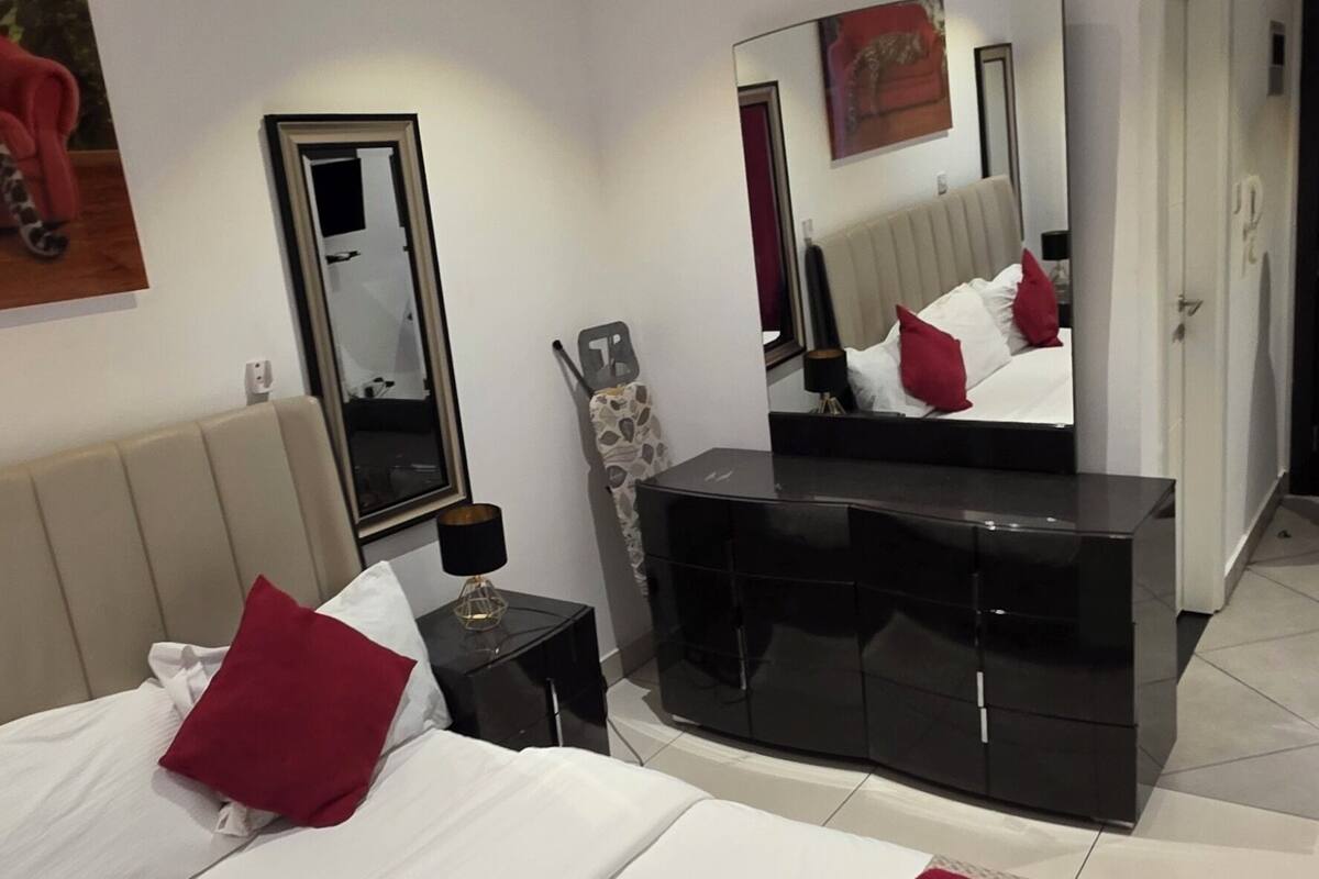 A hotel room with a bed, a dresser, a mirror, and a door.