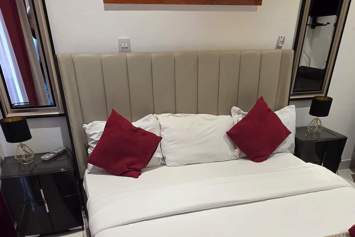 A hotel room with a large bed, two nightstands, a red sofa, and a leopard print cushion.
