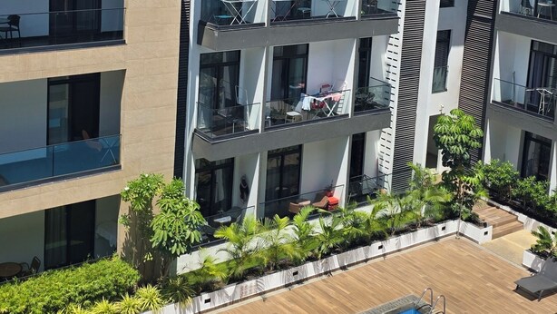 A multi-story building with balconies, a swimming pool, and surrounding greenery. - ebs properties ghana (Accra)