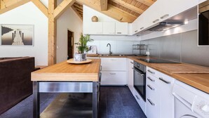 Una cocina moderna con vigas de madera, armarios blancos, electrodomésticos de acero inoxidable y una isla de madera.