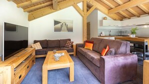 Una sala de estar con televisor, muebles de madera, un sofá y una mesa de centro.