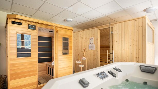 Una sala de sauna con paredes de madera, un jacuzzi y un panel de control.