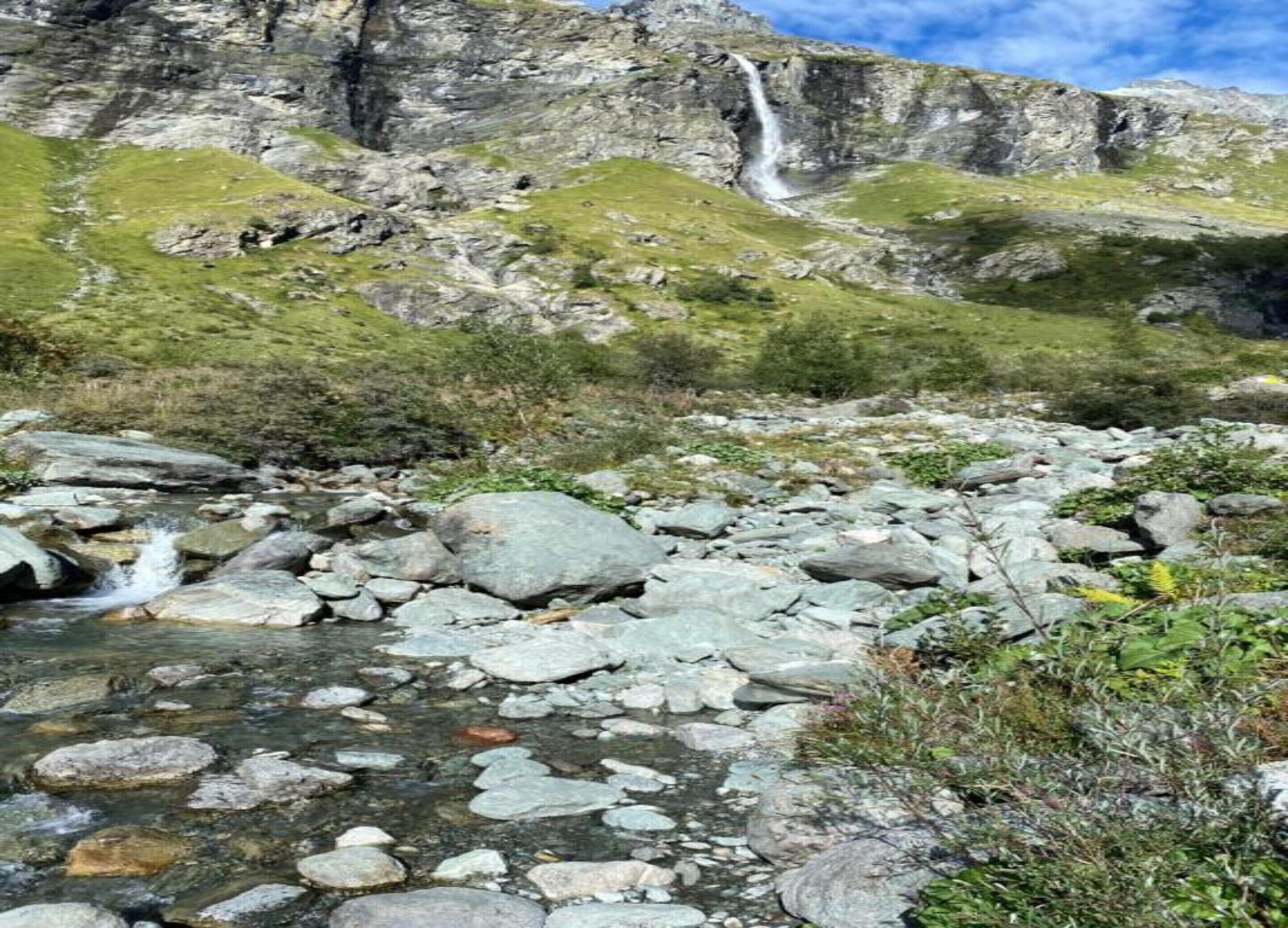 A rocky stream with a waterfall in the background.