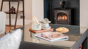 Een glazen tafel met een tijdschrift, een theepot, kopjes en koekjes.