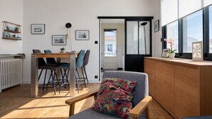 En moderne stue med spiseplads, en træbænk, en radiator og udsigt gennem en glasdør.