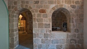 A stone corridor with arched doorways, a lamp, and a table with a pitcher. - Vivila in the medieval city of Rhodes (Rodos)