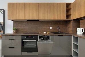 Una cocina moderna con armarios de madera, horno empotrado, lavavajillas y pileta.