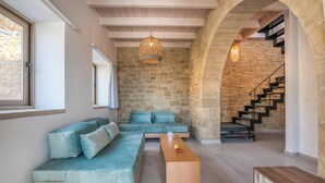Ein modernes Wohnzimmer mit Steinwand, Holztreppe und großem Fenster.