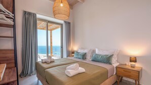 Ein Schlafzimmer mit Bett, Nachttischen, einer Hängeleuchte und Meerblick.