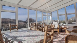 Une véranda aménagée avec un lit, des chaises et une table, offrant une vue sur la campagne.