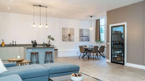Een moderne woonkamer met een bank, een salontafel en een eethoek met stoelen en een tafel.