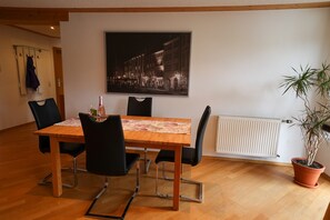 Ein Essbereich mit Holztisch, schwarzen Stühlen, einem Blumentopf und einem gerahmten Bild an der Wand.