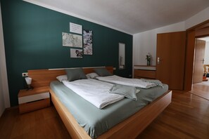 Ein Schlafzimmer mit einem hölzernen Bett, einem Nachttisch, einer Schublade, einem Spiegel und Bildern an der Wand.