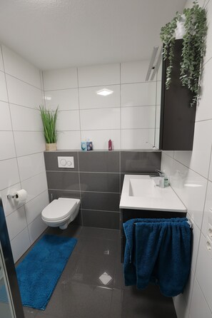 Ein Badezimmer mit Toilette, Waschbecken, blauem Handtuch und einer Topfpflanze.