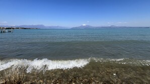 Ein klarer Blick auf einen See mit einem Steg, ruhigem Wasser und fernen Bergen unter blauem Himmel.