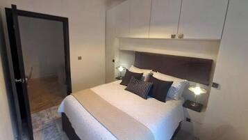 A bedroom with a bed, bedside lamps, a headboard, and a door.
