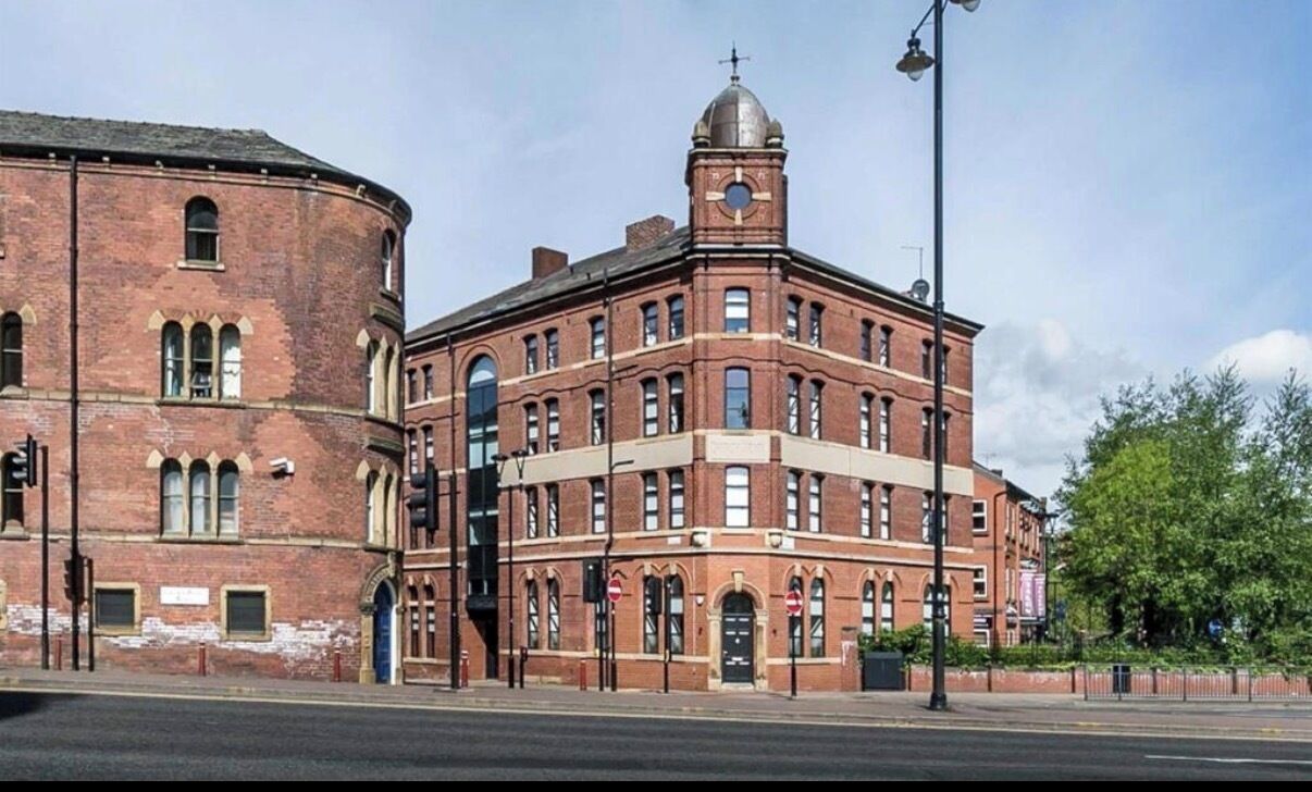 A large brick building with a clock tower, arched windows, and a dome.