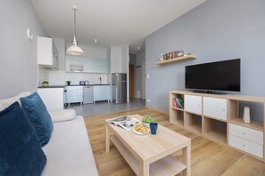 Un salon moderne comprenant un canapé, une table basse, un téléviseur et un coin cuisine.
