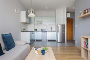 Une cuisine moderne avec des meubles blancs, un réfrigérateur en acier inoxydable et un coin repas comprenant une table et des chaises.
