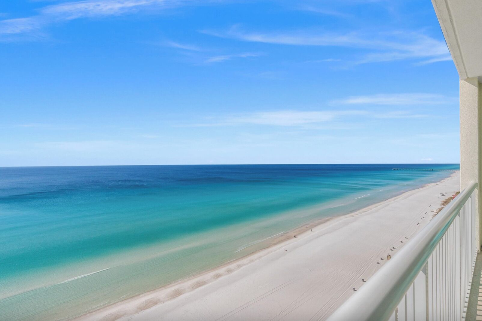 A beach view from a balcony with a clear sky.