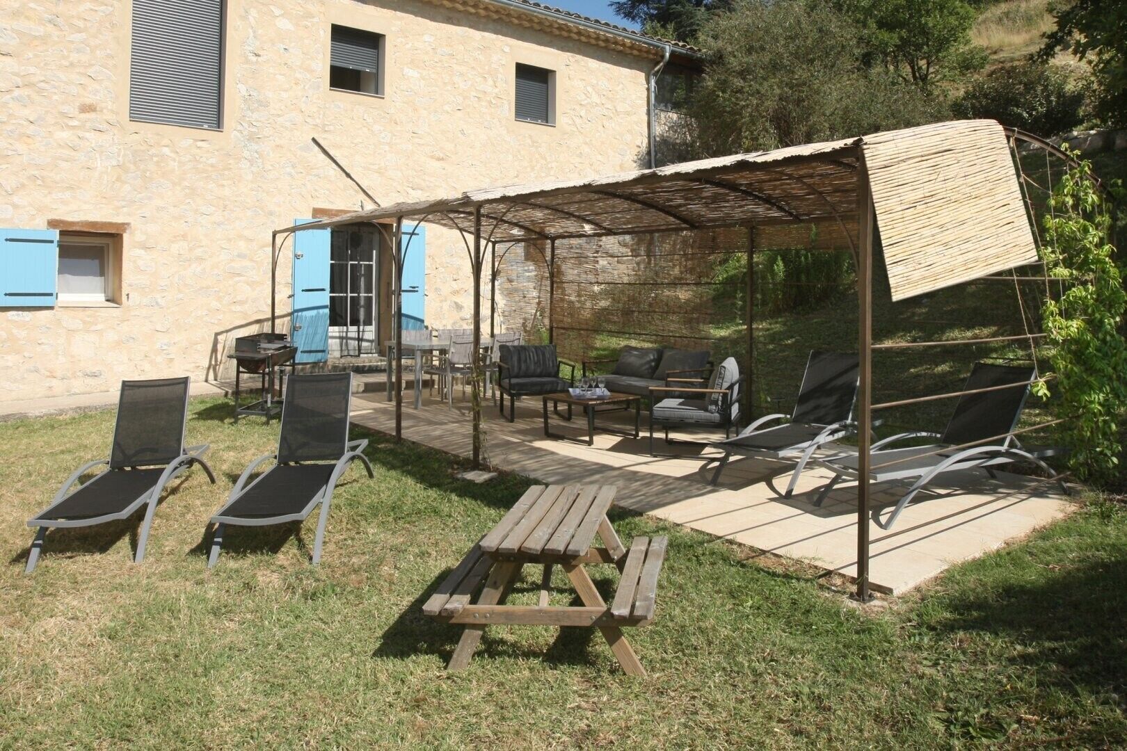 A patio with outdoor furniture, a covered seating area, and a stone building in the background.
