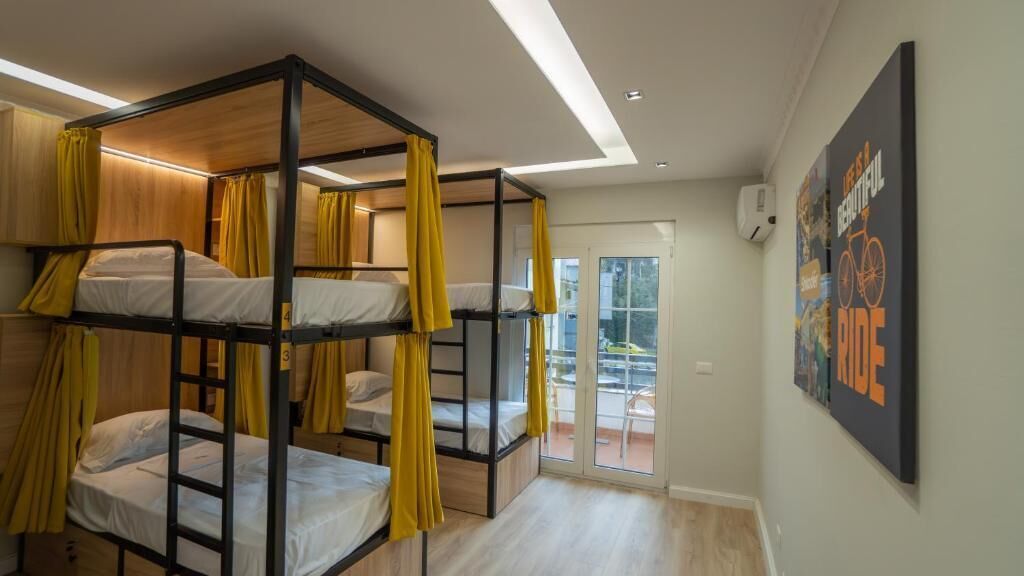 A dormitory room with bunk beds, a balcony with a chair, and a motivational poster on the wall.