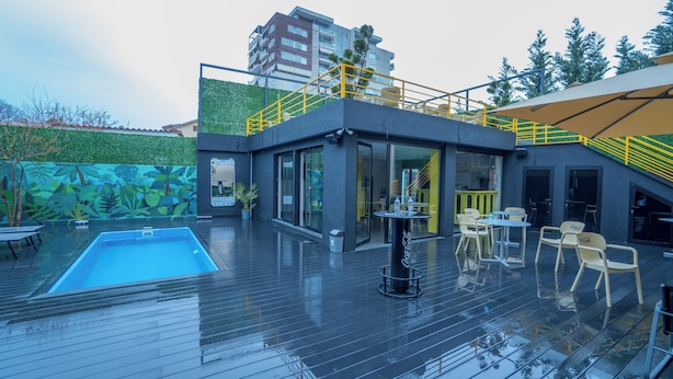 A modern outdoor pool area with a glass enclosure, outdoor seating, and a staircase leading to an upper level. - 7even Boutique Hostel (Tirana)