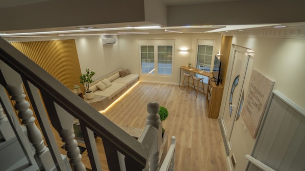 A modern interior with a wooden floor, a sofa, a dining area, and a staircase. - 7even Boutique Hostel (Tirana)