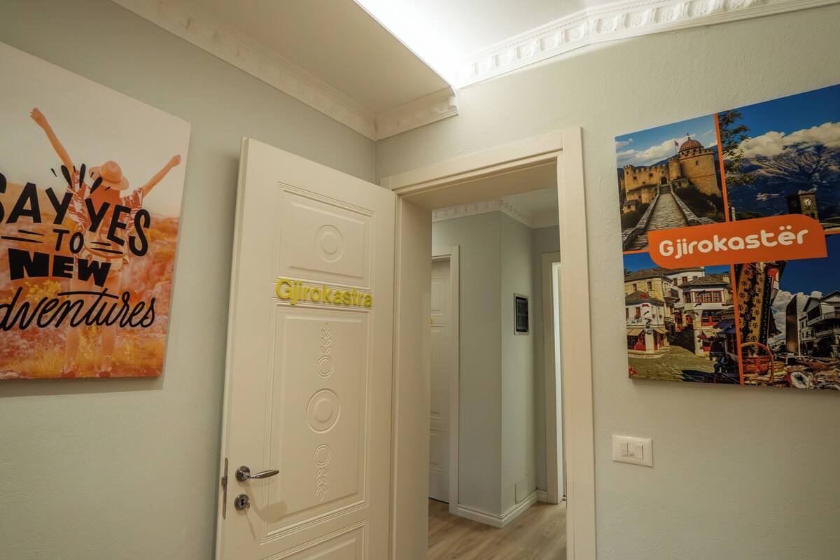 A hallway with a door labeled 'Girokaster' and a wall with a poster titled 'SAY YES TO NEW Adventures.'