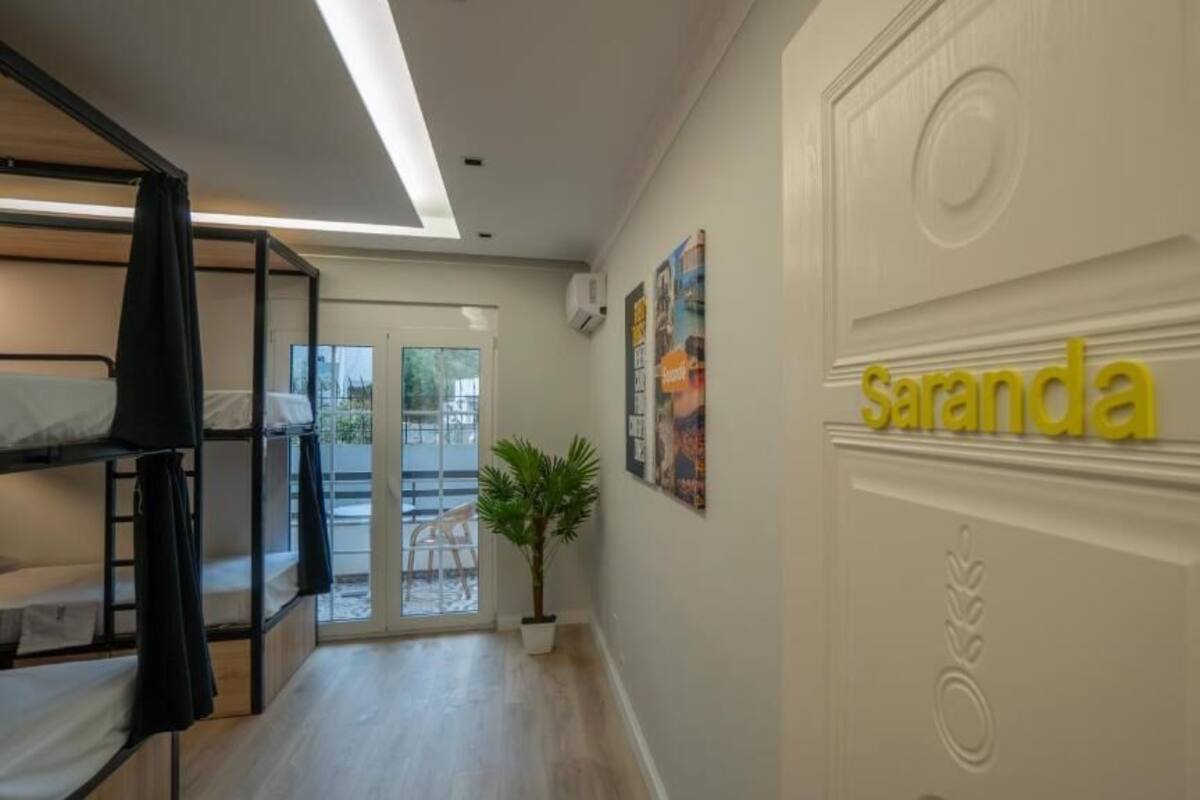 A hotel room with bunk beds, a potted plant, and a door with the name 'Sambra' on it.