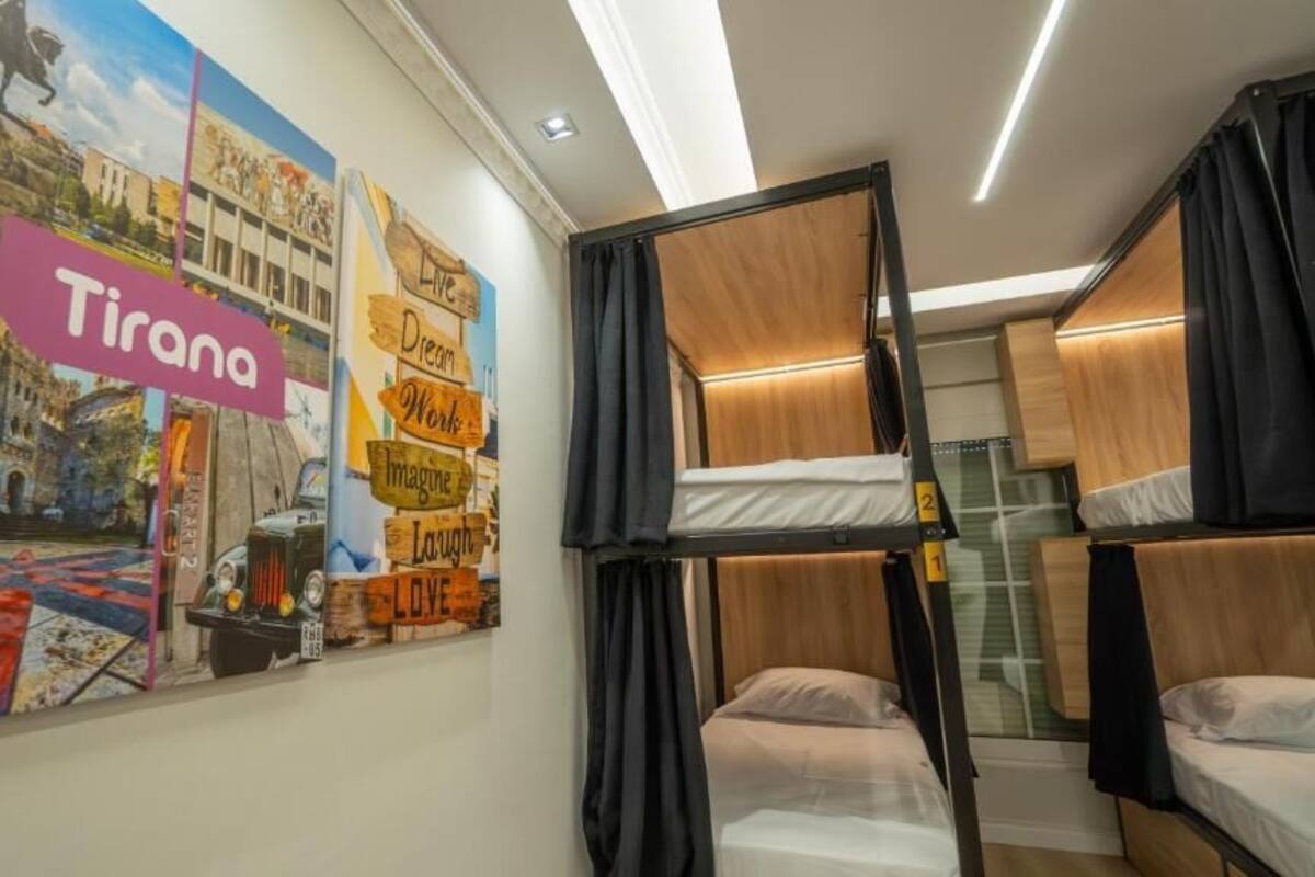 A room with bunk beds, a mural with the word 'Tirana,' and a mirror.