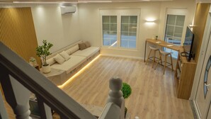 A modern living space with a sofa, a dining area, and a staircase. - 7even Boutique Hostel (Tirana)
